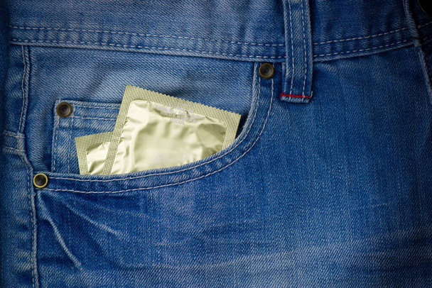 Para prezerwatyw w przedniej kieszeni dżinsów. Koncepcja HIV i AIDS. Zakażenia przenoszone drogą płciową. Kopiuj space.STI - Zdjęcie, obraz
