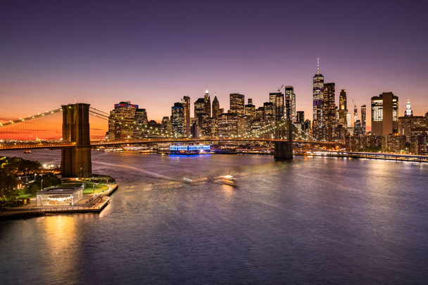 Brooklyn Bridge on the East River and the Manhattan downtown city skyline at night in New York USA. - Foto, imagen
