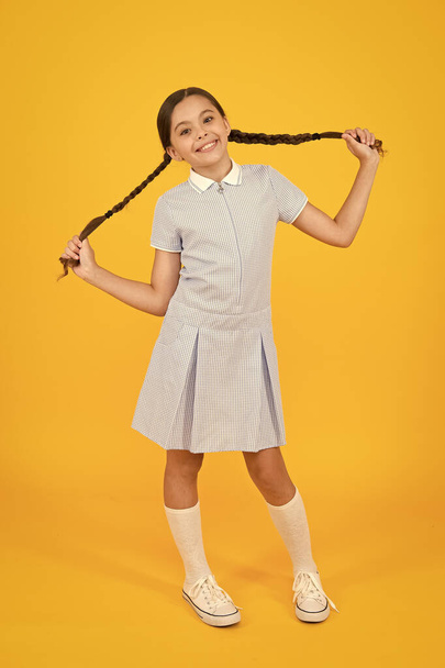 zorgeloze leerling. klein meisje in school uniform. retro-look. kind in vintage stijl. Old school. Kid mode. gelukkig kind op gele achtergrond. mode en schoonheid. jeugd geluk. grappig humeur - Foto, afbeelding