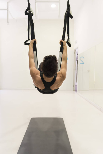 A professional female aeropilates performs exercises hanging from ribbons - Φωτογραφία, εικόνα