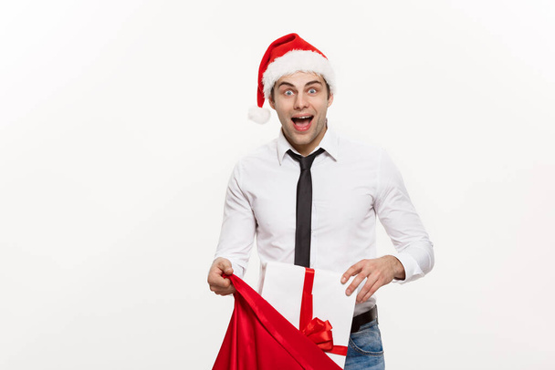 Concepto de Navidad - Hombre de negocios guapo celebrar feliz Navidad y feliz año nuevo desgaste sombrero de santa con Santa bolsa grande roja
. - Foto, Imagen