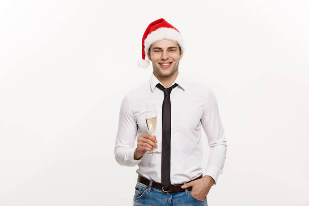 Kerstconcept - Knappe zakenman vieren vrolijk kerstfeest en gelukkig nieuwjaar dragen kerstmuts met glas champange. - Foto, afbeelding