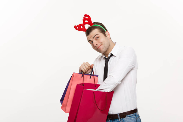 クリスマスのコンセプト-ハンサムなビジネスマンは陽気なクリスマスを祝うと幸せな新年はトナカイのヘアバンドを着用し、サンタ赤の大きな袋を保持. - 写真・画像