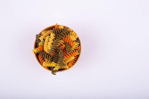 Un tazón de madera de pasta en espiral colorida - Foto, Imagen