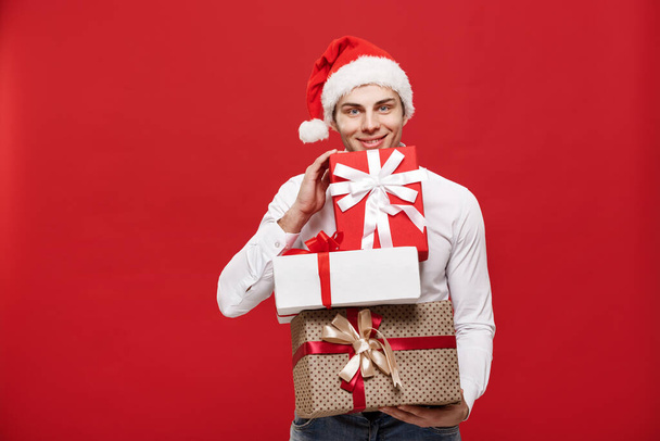 Christmas Concept - Komea valkoihoinen onnellinen liikemies, jolla on paljon lahjoja, joissa on kulumista jouluhattu poseeraa valkoisella eristetyllä taustalla
. - Valokuva, kuva