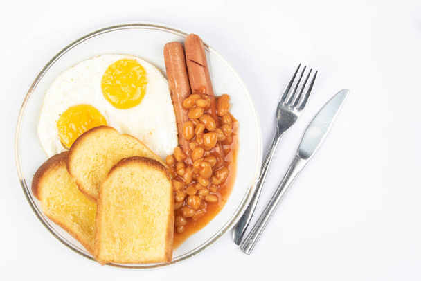 Anglická snídaně se smaženými vejci, klobásami, fazolemi a tousty na bílém pozadí. - Fotografie, Obrázek