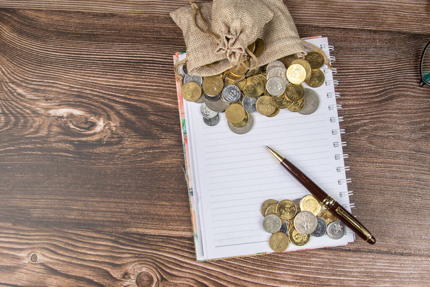 Torba na monety i pusty notes do zapisu na drewnianym stole - Koncepcja oszczędzania. - Zdjęcie, obraz