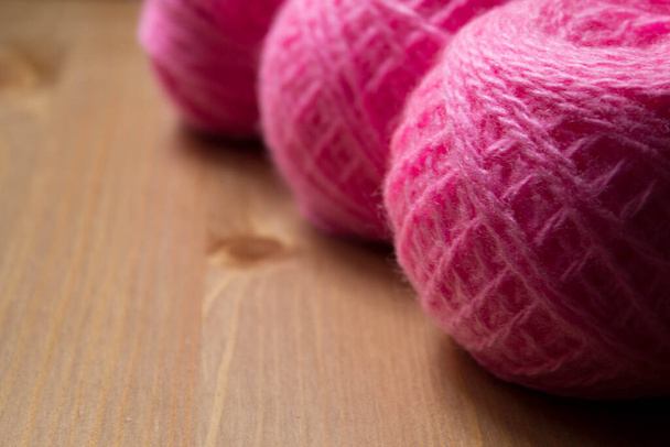 Loisirs et travaux à l'aiguille (tricot). Des boules de fil à tricoter rose vif sur une table en bois en perspective avec mise au point sélective près - vers le haut avec espace de copie. - Photo, image