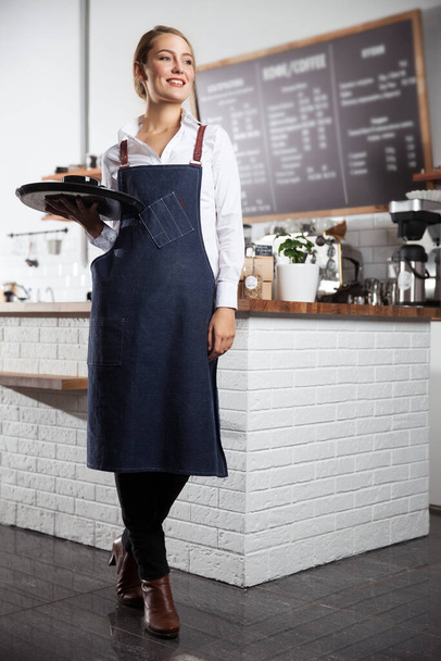 Happy waitress holding a tray with a cup of coffee - Foto, immagini