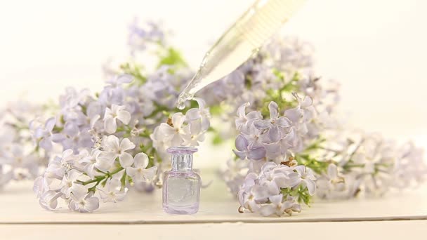 Ουσία των λουλουδιών σε λευκό φόντο σε όμορφο γυάλινο βαζάκι - Πλάνα, βίντεο