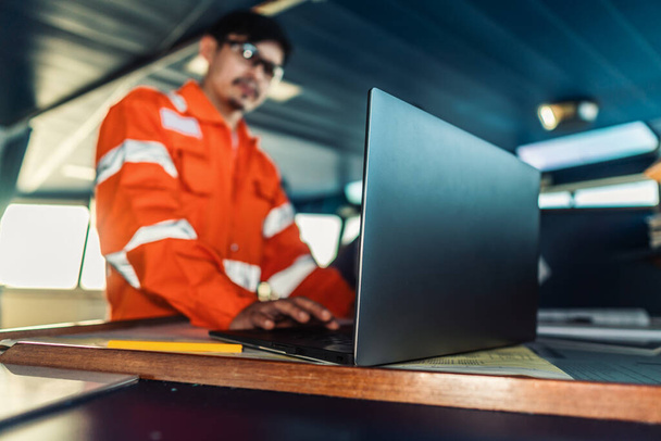 Filipiński oficer pokładowy na mostku statku lub statku. Używa laptopa, elektronicznych dokumentów na morzu. - Zdjęcie, obraz