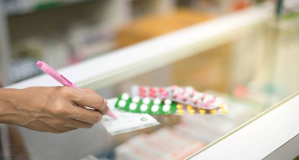 Pharmacienne préparant une pharmacie de capsules à vendre à un patient pour le protéger à la pharmacie. Pour un concept sain. - Photo, image