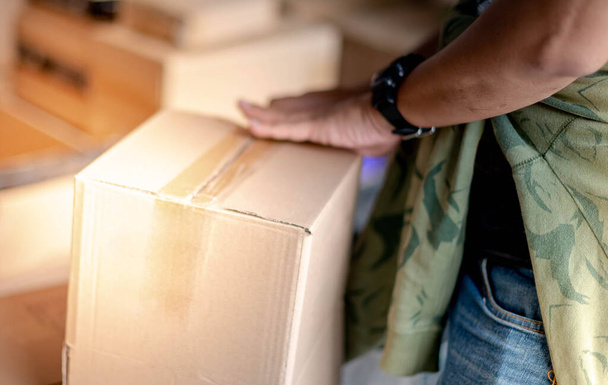 mężczyzna ręczne uszczelnienie kartonowe pudełko z dozownikiem taśm do przygotowania do dostawy do klienta online w magazynie.  - Zdjęcie, obraz