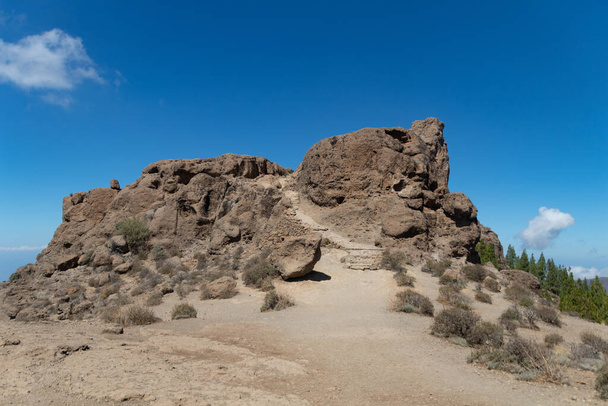 Monument naturel en pierre avec un sentier intérieur dans une région désertique, sous un ciel bleu et quelques nuages - Photo, image
