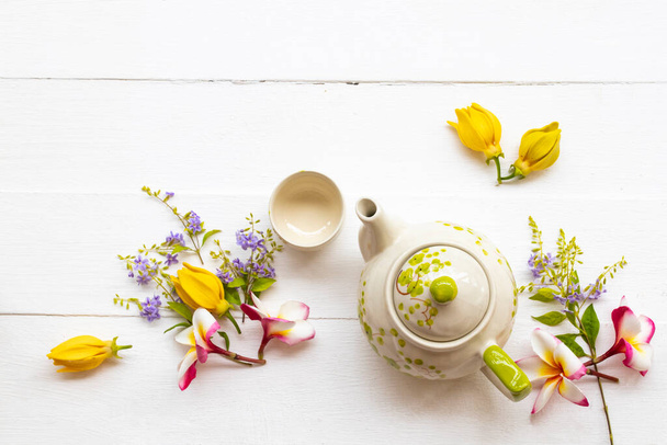 herbal healthy drinks hot tea for health care with teapot ,flowers frangipani ,ylang ylang arrangement flat lay style on background white wooden - Photo, image
