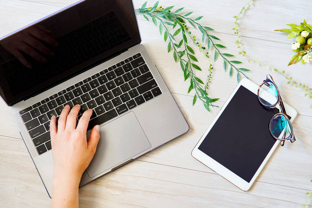 Ноутбук, планшет, окуляри та рослина, розміщені на білому дерев'яному столі
 - Фото, зображення