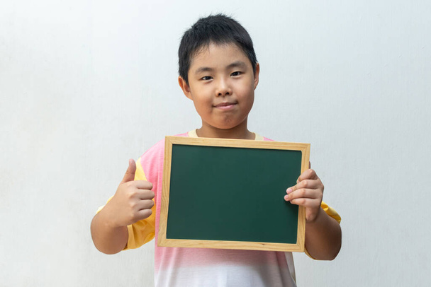 Asyalı çocuk boş tahtayı tutuyor. Eğitim kavramı - Fotoğraf, Görsel