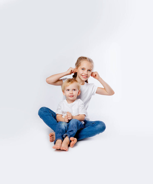 brother and sister in blue jeans and t-shirts hugging - Фото, изображение