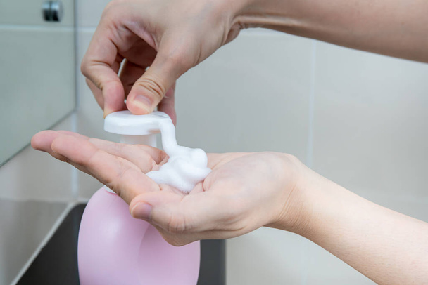 Женщина моет руки с помощью жидкого мыла для мытья рук для защиты от коронавируса 2019 года, риск заражения вирусом COVID-19. Мытье рук может повысить личную гигиену и защитить от вируса
. - Фото, изображение