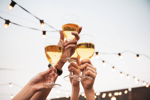 Group of people in party and celebrating together with white wine. Happy Asian people enjoy partying in festival and celebrate with white wine on the roof top bar and restaurant of 5 stars hotel. - Foto, afbeelding