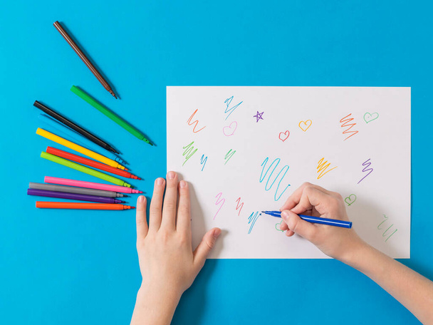 The child draws with colored markers on a white sheet. - Foto, Imagem