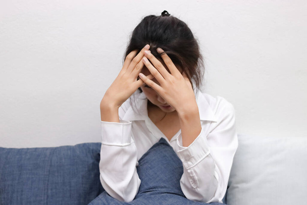 Ttired stressed young Asian woman covering face with hands in living room. - Foto, Imagem
