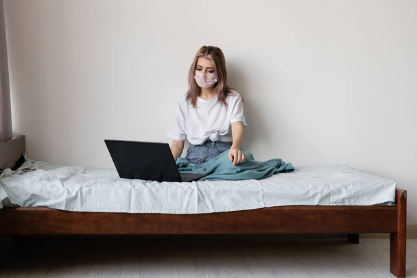 remote work. Young woman during illness is sitting at home on the couch. A face shield is worn. Laptop on hand. Perform your duties deleted. Place for text - Fotoğraf, Görsel