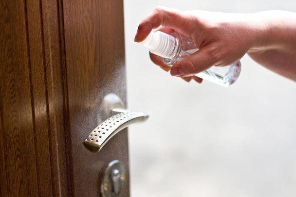 Actions to prevent the spread of COVID-19 coronavirus, door handle disinfection. Closeup of the hand wipes the door handle with a disinfectant - Фото, зображення