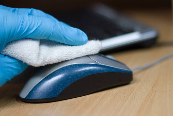 Σκουπίστε με αντιβακτηριδιακό σκουπίστε στην επιφάνεια ενός ποντικιού υπολογιστή. Απολύμανση επιφάνειας εργασίας Coronavirus COVID-19. - Φωτογραφία, εικόνα
