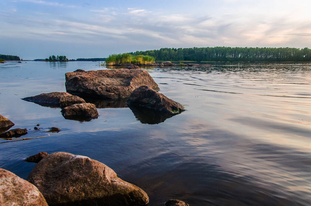The evening sky is reflected in the water of the lake. Finnish landscape on the lake. - Photo, Image