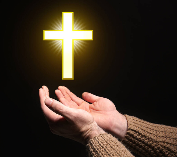 Руки религиозного человека и христианского креста на черном фоне
 - Фото, изображение
