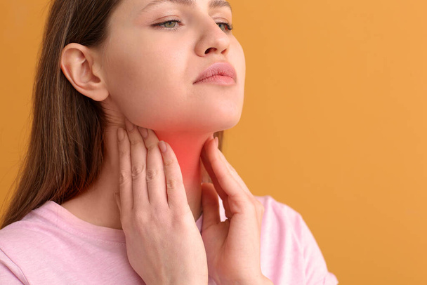 Young woman checking thyroid gland on color background - Photo, image