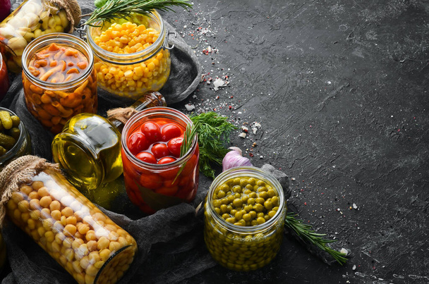 Food stocks in glass jars. Pickled vegetables. On a black background. Top view. - Foto, Bild