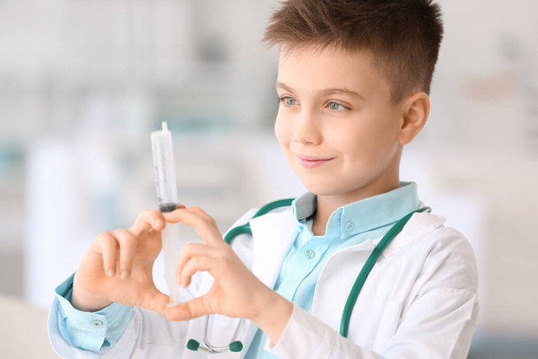 Cute little doctor with syringe in clinic - Фото, зображення