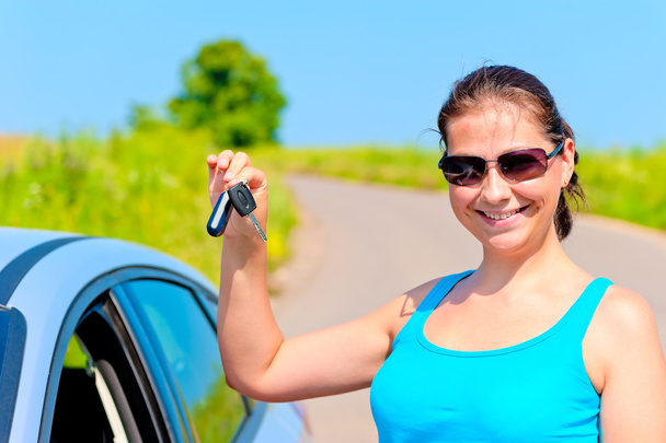 若い女性は誇らしげに彼女の新しい車にキーを表示します。 - 写真・画像