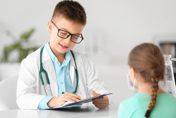 Cute little doctor working with patient in clinic - Foto, imagen