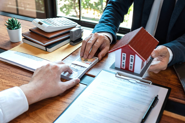 家を購入する売買契約、不動産屋は住宅ローンを提示しており、承認された不動産申請書で家を購入する契約を締結した後、顧客に鍵を与えています. - 写真・画像