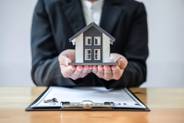 Immobilienmakler unterzeichnen Vertrag für Hausversicherung, der Käufe für Kunden mit Hausmodell und Schlüssel auf dem Tisch genehmigt. - Foto, Bild