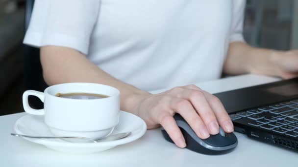 unrecognizable womans hands working on laptop keyboard and drinking coffee, close up - Πλάνα, βίντεο