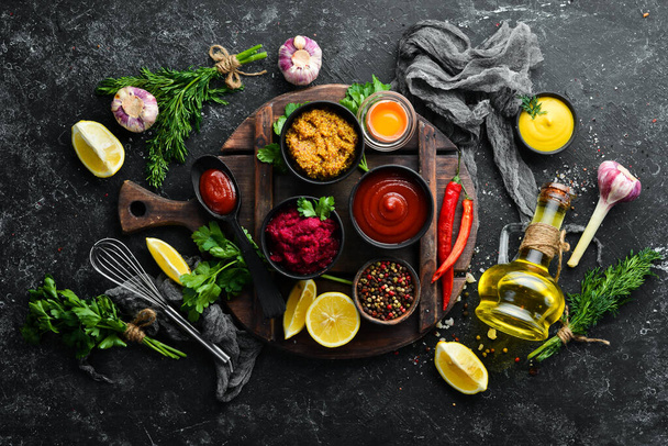 Set of colored sauces and spices on black stone background. Traditional sauces for meat and fish. - Foto, Imagen