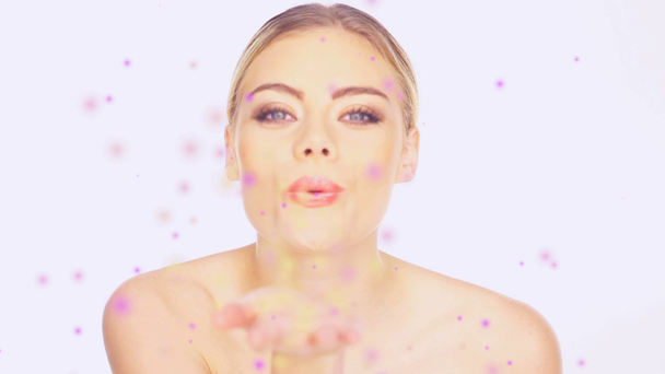 Kaunis nainen puhaltaa värikkäitä hiukkasia
 - Materiaali, video