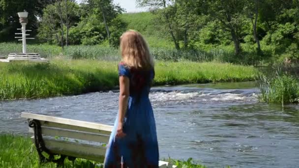 dziewczyna na ławce przez strumień - Materiał filmowy, wideo