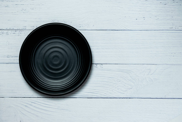 An empty plate resting on a white wooden floor. - Foto, imagen