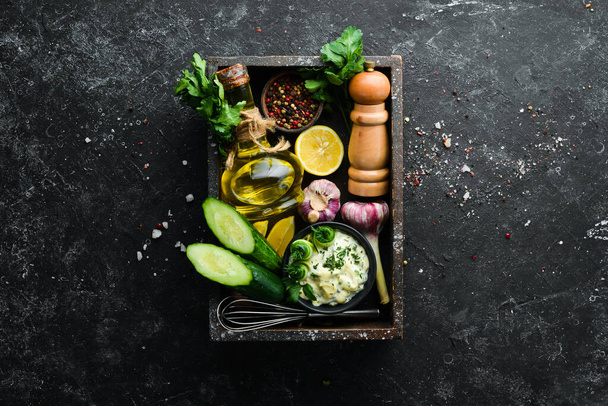 Homemade Greek sauce with cucumber, lemon and garlic on a black background. Top view. Free space for your text. - Foto, imagen