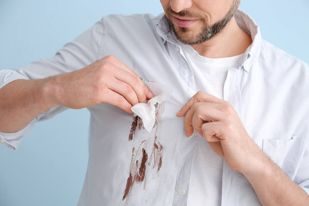 Homem limpando sujeira de roupas no fundo de cor
 - Foto, Imagem