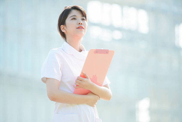 アジア人(日本人)の女性看護師が屋外で笑顔を見せる姿 - 写真・画像