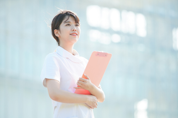 Портрет азиатской (японской) медсестры с улыбкой на открытом воздухе
 - Фото, изображение