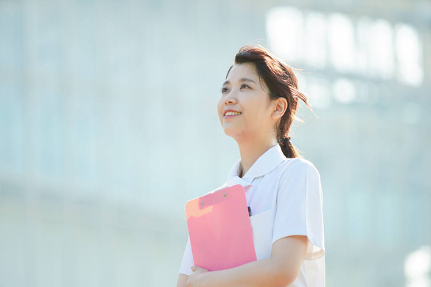 Retrato de uma enfermeira asiática (japonesa) mostrando um sorriso ao ar livre
 - Foto, Imagem