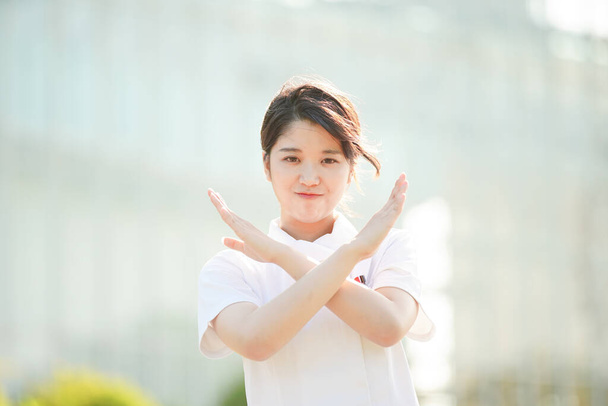 Une infirmière asiatique (japonaise) qui pose dans un refus en croisant les mains en diagonale
 - Photo, image