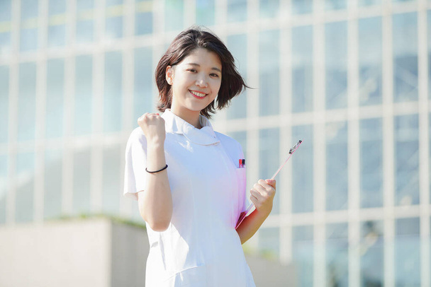 アジア人女性看護師がガッツポーズで笑顔で応援 - 写真・画像